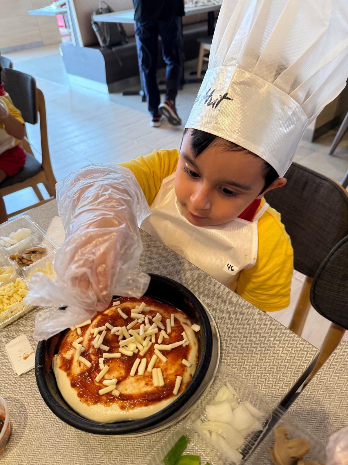 Child preparing pizza during a cooking activity